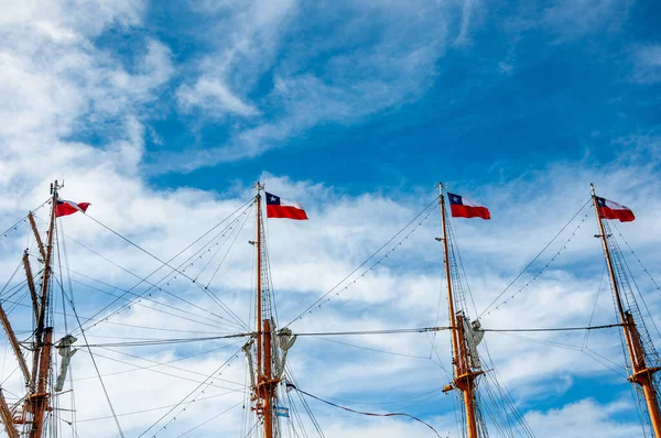 Flags of the Republic of Chile, on top of four masts waving with blue sky as background.