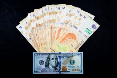 1000 Arjantin pesosunun hayranı ve arka planda 100 Amerikan doları banknot