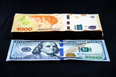 Comparison of a stack of 1000 Argentine peso notes with a 100 US dollar note. Inflation. Consequences of the monetary issue in Argentina. clipart