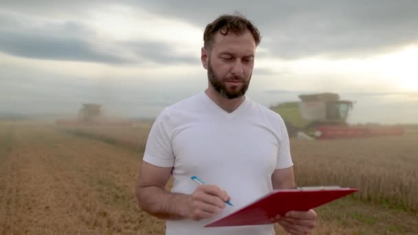 Zemědělec Tabulkou Pro Psaní Poznámek Stojí Poli Vedle Kombinuje Pracuje — Stock video
