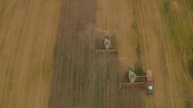 Buğday hasat eden bir tarladaki hasat makinesinin hava görüntüsü. Bir biçerdöver ve tarım makinesinin işi, üst görünüm.