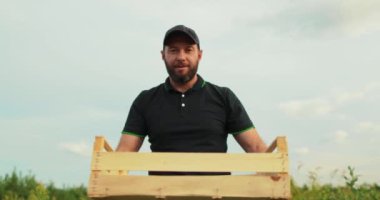 Dışarıda yabanmersini dolu bir kutu olan erkek çiftçi. Yabanmersini ekimi ve hasadı.