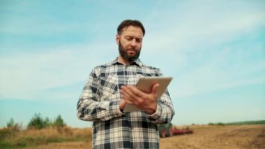 Tarladaki çiftçi tarım uzmanı. Çiftçi, işyeri sahibi buğday tarlasında tablete bakıyor. Elinde tablet olan bir tarımcı. Bir çiftçi-tarım uzmanı organik ürünleri kontrol eder. Tarım Çiftliği.