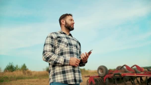 農場の農民アゴノミスト 小麦畑でタブレットを見ている農民 タブレットを手に持った農学者 農家経営者は有機農作物をチェックする エコカルチャーファーム — ストック動画
