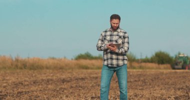 İşadamı çiftçi, tablet bilgisayarla sahada yürüyor. Modern tarım teknolojisi, tarlada dijital tabletle çalışan çiftçi