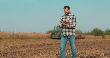 İşadamı çiftçi, tablet bilgisayarla sahada yürüyor. Modern tarım teknolojisi, tarlada dijital tabletle çalışan çiftçi
