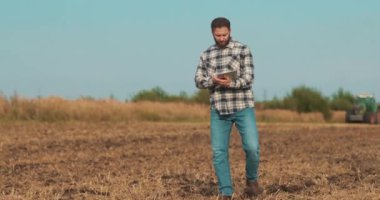 İşadamı çiftçi, tablet bilgisayarla sahada yürüyor. Modern tarım teknolojisi, tarlada dijital tabletle çalışan çiftçi