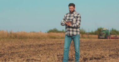 İşadamı çiftçi, tablet bilgisayarla sahada yürüyor. Modern tarım teknolojisi, tarlada dijital tabletle çalışan çiftçi