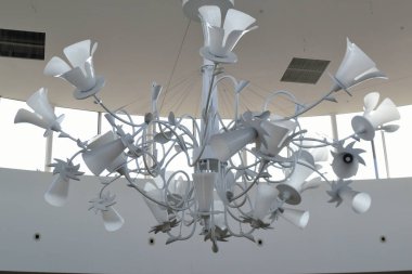 Mavi gökyüzü olan bir pencereye karşı tavanda avize