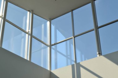 Alışveriş merkezinin cam pencereleri. Mavi gökyüzü. Beyaz duvarlar