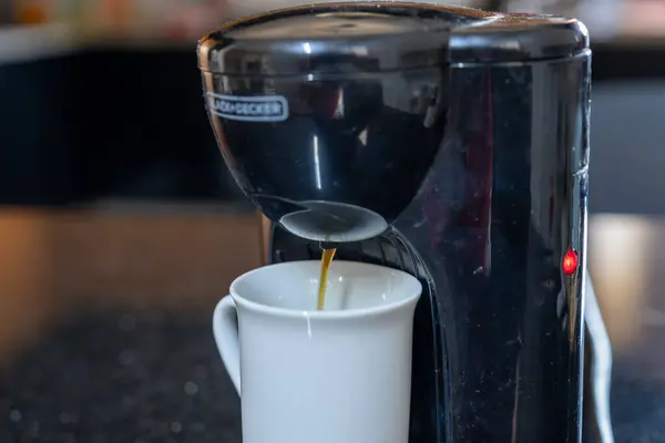 Coffee maker filling cup of coffee