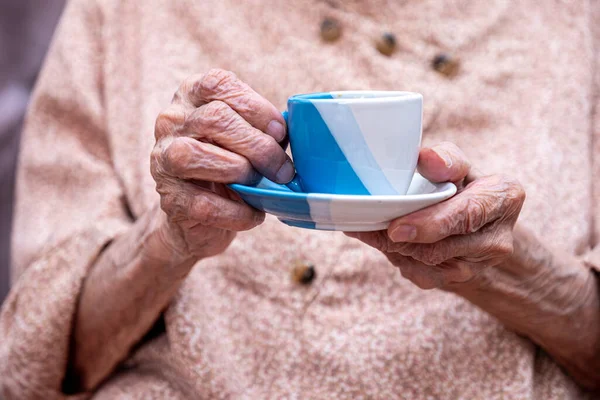 Old woman drinking coffee with smile on her face