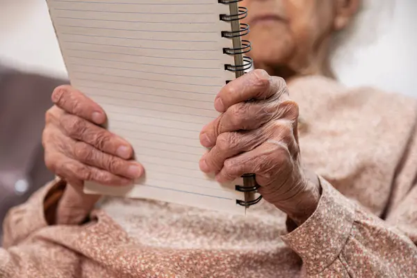 wrinkled hands for elderly person writing notes on his note book