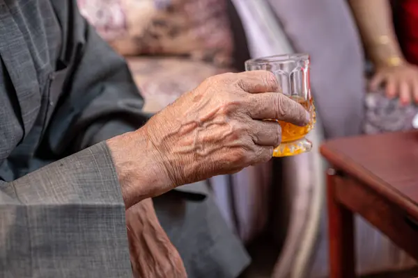 Arabic old man drinking tea and holding glass of tea in his hand