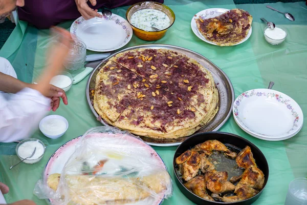 Family and friends gathering together at home for eating palestinian traditional musakhan