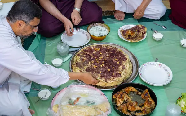 Family and friends gathering together at home for eating palestinian traditional musakhan
