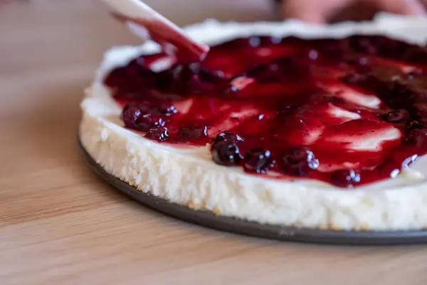 preparing cheesecake with red syrup of red berries and strawberries with cheesecake pan