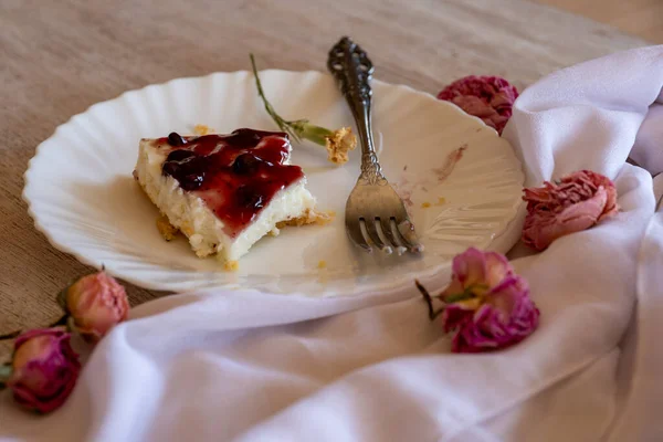 Cold cheesecake with cherry jelly served on wooden table with forks flowers roses and green veil