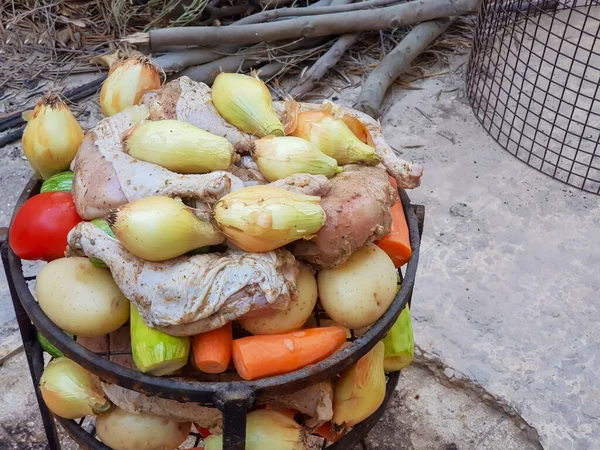 Zurbian dinner. The barrel has been uncovered and it is ready and well cooked. It contains chicken, vegetables and rice. It is placed on a wire rack and it has been transferred to the serving tray.