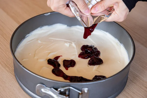 preparing cheesecake with red syrup of red berries and strawberries with cheesecake pan
