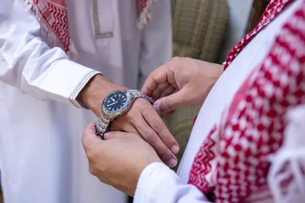 An Arab man gives his Arab friend a wristwatch