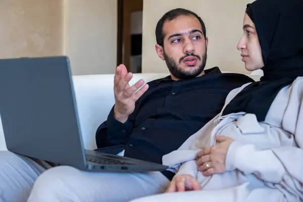 male and pregnant female chatting about pregnancy and how to rise child while using laptop  in home wearing black and grey