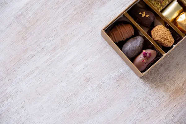 Top-View of Luxury Chocolate Box with Multiple Varieties in Stunning Golden Hues. Elegant Packaging with Copy Space. Perfect for Celebrations, Gifts, and Indulgent Occasions