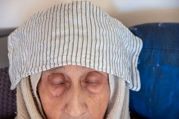 Old lady using wet towel to stop headache and high body temperature
