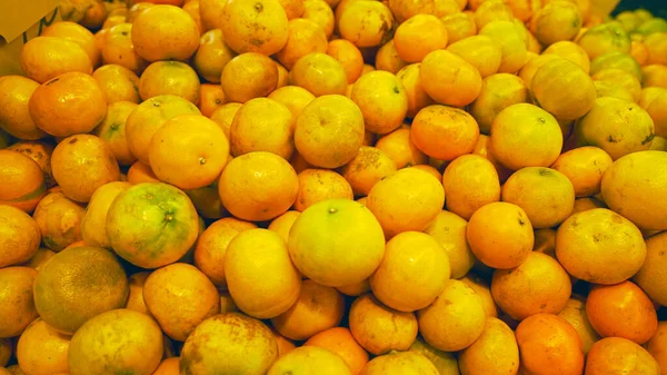 heap of fresh mandarin oranges in Asian traditional market. ugly fruit