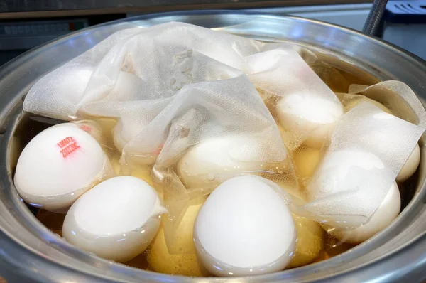 Mutfak lezzetlerine hazırlanan bir tencere taze, pişmemiş yumurtaları lezzetli çay yumurtalarına dönüştürecek şekilde tutar. Her yumurta, üretim tarihlerini ve yollarını gösteren bir izleme koduna sahiptir..