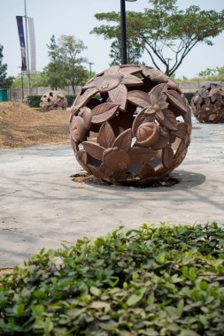  Kaldırımın kenarına yerleştirilmiş yuvarlak bir top şeklinde bir yaprak heykeli. Ağaçlara karşı kaldırımda taşın yakın çekimi