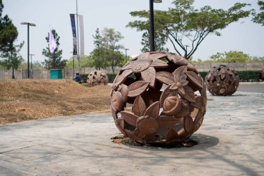  Kaldırımın kenarına yerleştirilmiş yuvarlak bir top şeklinde bir yaprak heykeli. Ağaçlara karşı kaldırımda taşın yakın çekimi