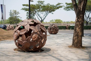  Kaldırımın kenarına yerleştirilmiş yuvarlak bir top şeklinde bir yaprak heykeli. Ağaçlara karşı kaldırımda taşın yakın çekimi