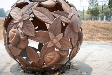  Kaldırımın kenarına yerleştirilmiş yuvarlak bir top şeklinde bir yaprak heykeli. Ağaçlara karşı kaldırımda taşın yakın çekimi