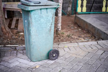 Yeşil çöp tenekeleri yolun kenarında. Rengi solmaya başlayınca yıpranmış görünüyor.. 