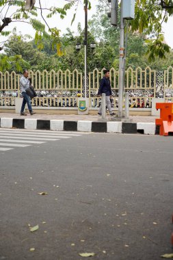 Tangerang, Banten. 14 Ekim 2023 - insanlar kaldırımda turuncu ulaşım servis engelleriyle yürüyorlar..