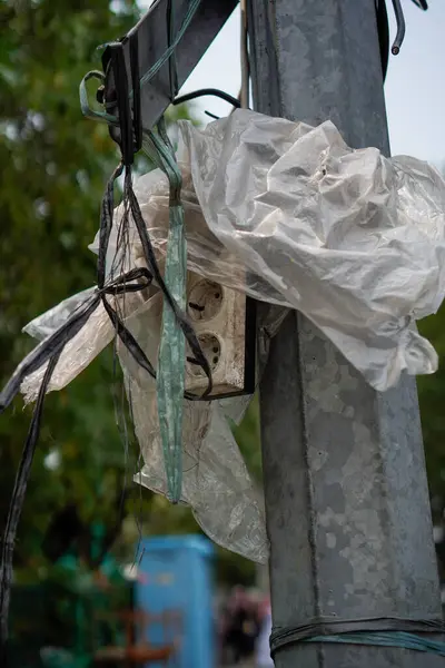 The electrical socket is wrapped in plastic, located on an electrical stand to protect it from rainwater.Format Foto