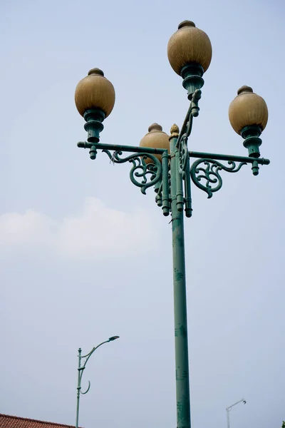 courtyard lamp with a tall pole, seen from below with a view towards the sky.