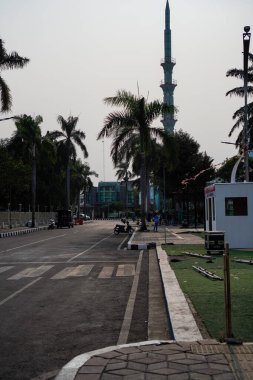 Tangerang, Banten. 14 Ekim 2023 - Tangerang şehrinin sokakları, arka planda uzun cami kulesi olan sürücülerle meşgul olmaya başladı.. 