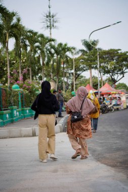 Tangerang, Banten. 14 Ekim 2023 - Arkadan, eşarp takan iki kadının paralel bir açıdan yürüdüğü görüldü.. 