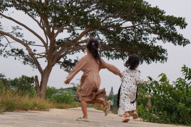 Kurak mevsimde pirinç tarlasında oynayan iki küçük kız. Arkadan görünüyor. 