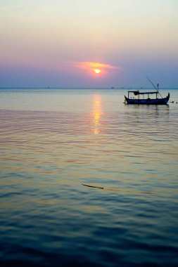 Arka planda batan güneş varken park halindeki tekneden uzağa bakıyorum.. 