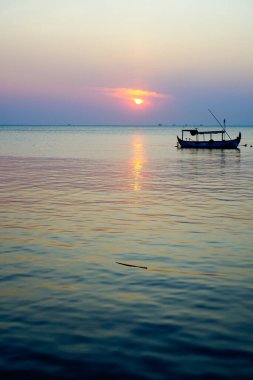 Arka planda batan güneş varken park halindeki tekneden uzağa bakıyorum.. 