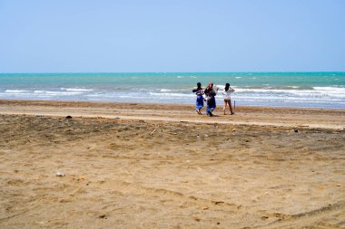 Jepara, Central Java 'dan. 27 Ekim 2023 - Müslüman kıyafetleriyle plajda oynayan genç kadınlar. 