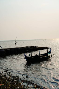 Öğleden sonra sahile dayanan bir tekne, arka planda gökyüzüne karşı yakından görülüyor. 