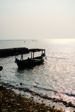 Öğleden sonra sahile dayanan bir tekne, arka planda gökyüzüne karşı yakından görülüyor. 
