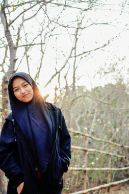 Güneşin arka planına başörtüsü takmış, ağaçlardaki boşluklardan geçen Javalı bir kadının güzel görünüşü.. 