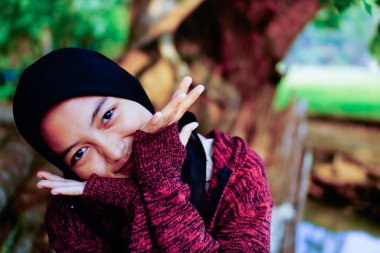 Güzel bir kadının iki eli yanaklarının yanında ve başı hafifçe yana yatmış bir görüntüsü. 