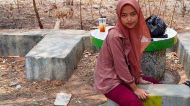 Kurak mevsimin arka planında tesettür takan bir Cava kadınının güzel görünüşü. 