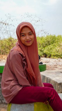 Kurak mevsimin arka planında tesettür takan bir Cava kadınının güzel görünüşü. 